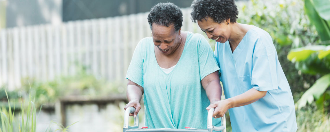 Younger woman helping older woman on a walker